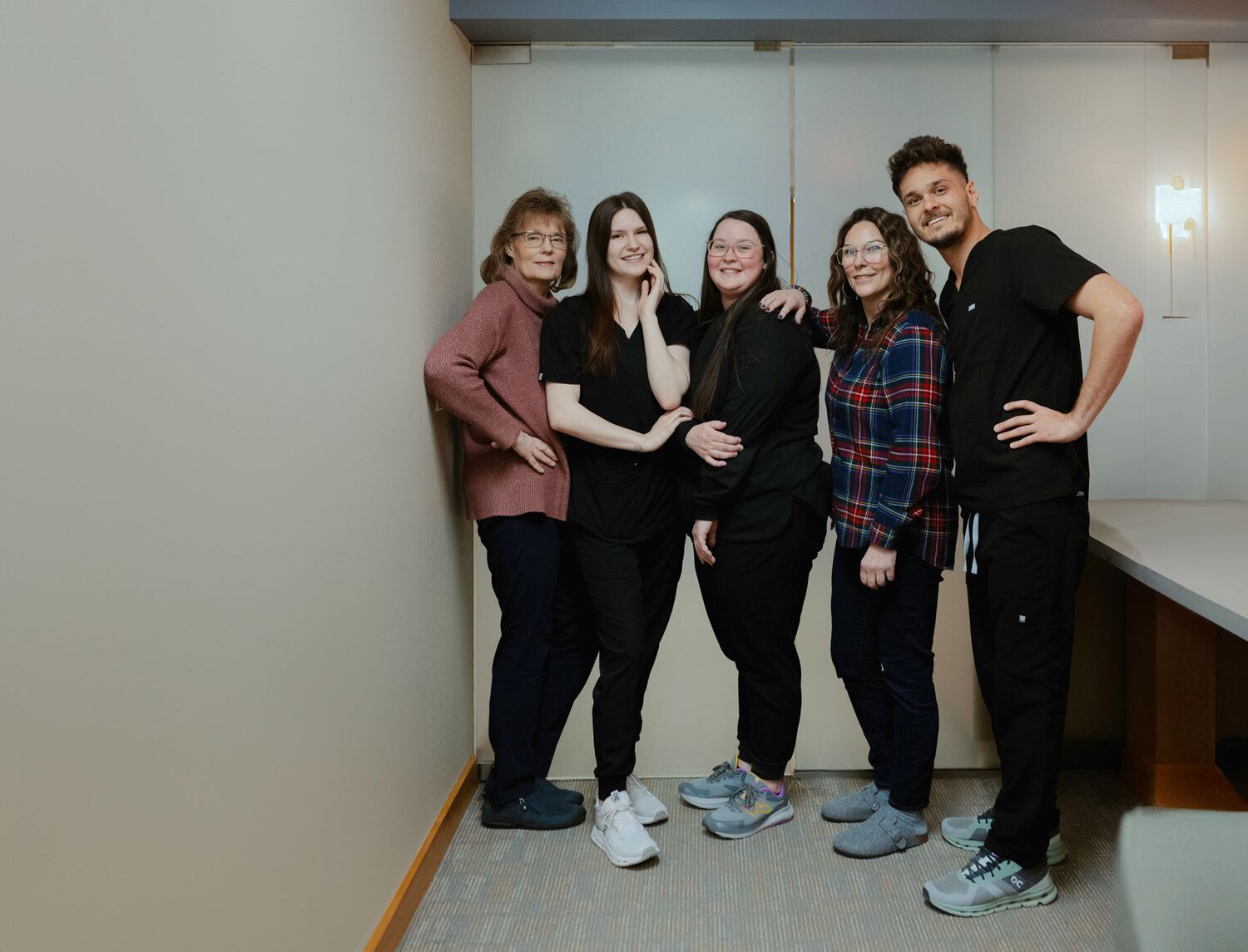 Staff members at Periodontics and Implant Solutions office, smiling and posing together in a hallway, wearing a mix of scrubs and casual attire.